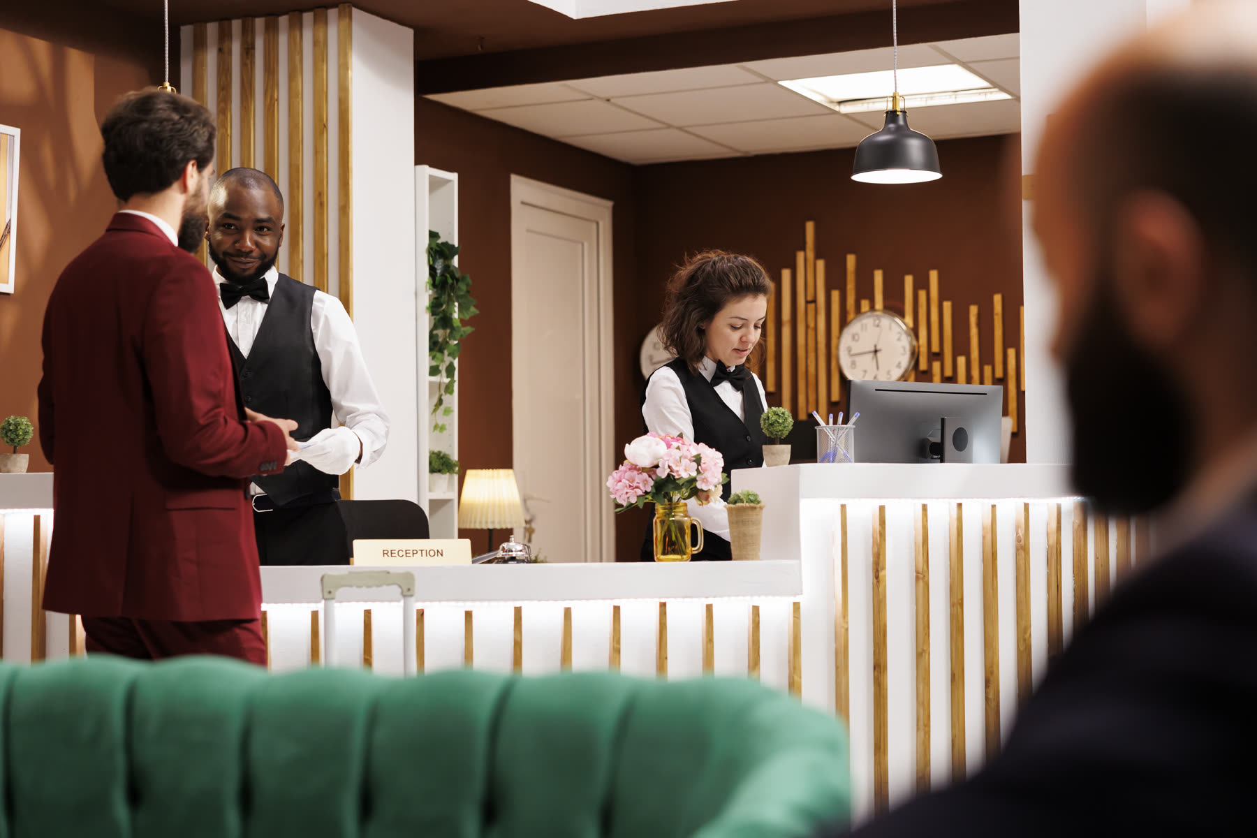 A hotel lobby with the front desk team welcoming a guest